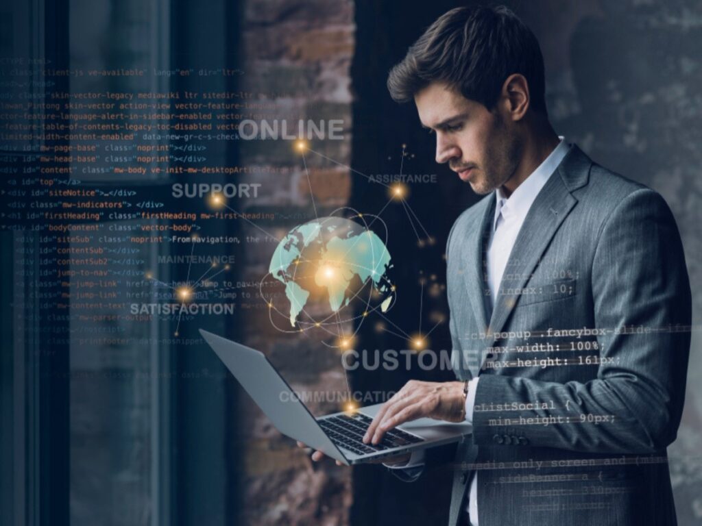 How to describe your business with AI, the image depicts a professional working on a laptop, surrounded by digital elements such as code, a globe, and various words like "ONLINE," "SUPPORT," "CUSTOMER," and "COMMUNICATION." The visual suggests a focus on technology, global connectivity, and customer service.